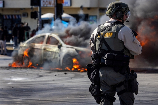 Smoke rises from a burning car on Atlantic Boulevard during a standoff by protesters and law enforcement, following multiple detentions by U.S. Immigration and Customs Enforcement in Compton, Calif., June 7, 2025.
