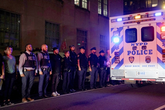 New York City police officers stand at attention for the ambulance transfer of slain NYPD officer Didarul Islam at New York-Presbyterian/Weill Cornell Medical Center in New York City early July 29, 2025. Islam, who was working an off-duty assignment, and multiple people were killed July 28 after a gunman opened fire at a midtown Manhattan skyscraper housing the offices of the NFL and prominent financial and real estate firms. 