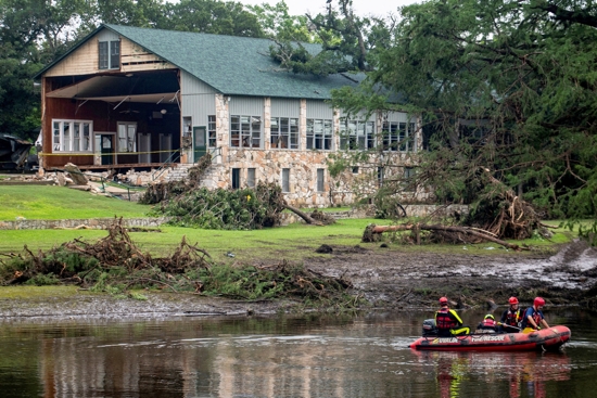 Search teams continue searching for flood victims in front of the main building at Camp Mystic in Kerr County, Texas, July 7, 2025, in the aftermath of deadly flooding. Flash floods in Texas killed more than 100 people over the Fourth of July holiday weekend, including girls attending a summer camp, and left others still missing.