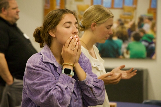 At left, Ellie Shaw, coordinator of middle school youth ministry at St. John the Baptist in New Brighton, prays during a praise and worship session at a Youth Discipleship and Faith Formation orientation Aug. 18-19 in St. Joseph Hall at the Archdiocesan Catholic Center (ACC) in St. Paul.