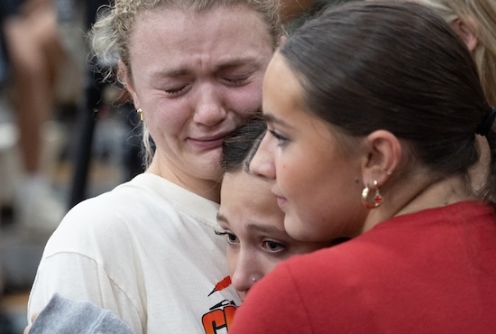 Ellie Mertens, left, youth minister at Annunciation church in Minneapolis, hugs others attending a prayer service at the Academy of Holy Angels in Richfield Aug. 27 to support those affected by a shooting at the church that morning, Mertens was at the Mass in the church when the shooting occurred.