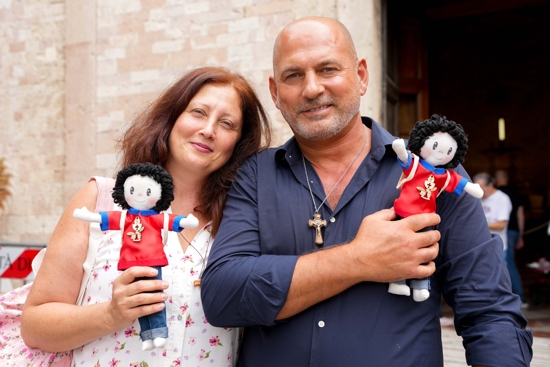 Fiorella Sacco and her husband, Massimo Mennelli, pose with handmade dolls representing Blessed Carlo Acutis during a pilgrimage in Assisi, Italy, Aug. 21, 2025. Sacco, who is a catechist with her husband, created the dolls with other volunteers at their parish of St. Joseph the Artisan in San Severo, Foggia, Italy.