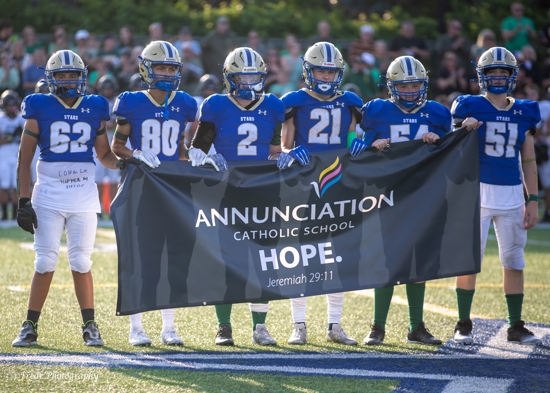 Academy of Holy Angels football players hold an Annunciation banner on the field before their season opener Aug. 29 against Byron.