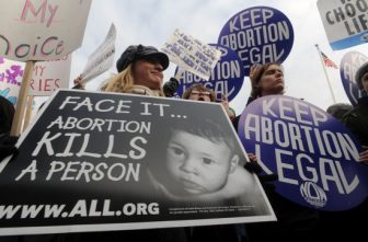 Maria Burud, left, of Madison, Wis., is pictured in a file photo holding a pro-life sign next to demonstrators for legal abortion outside the Supreme Court building in Washington. On July 2, 2025, Wisconsin's Supreme Court struck down the state's 176-year-old abortion ban in a 4-3 ruling. (OSV News photo/CNS file, Peter Lockley)
