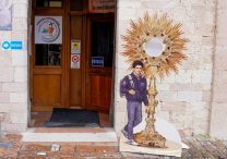 A sign featuring Blessed Carlo Acutis stands outside the Church of St. Mary Major in Assisi, Italy, April 1, 2025.
