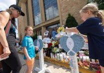 From left, Brook Steege and her daughters, Daisy and Rosie, visit a memorial outside Annunciation Church in Minneapolis Aug. 28, the day after a shooting took place during Mass. Both girls are students at the school and were attending the Mass when the shooting took place. Rosie is a third grader and Daisy is a first grader. The family, which also includes Brook's husband, Brandon Steege, are parishioners of Annunciation. DAVE HRBACEK  |  THE CATHOLIC SPIRIT