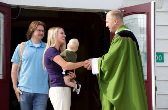 Maria Warnock and her husband, Zach, greet Father Ryan Glaser outside St. Agatha in Coates on Aug. 3. Father Glaser said he and Maria attended grade school together.  THE CATHOLIC SPIRIT  |  JOSH MCGOVERN