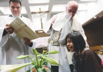 In this file photo from 2019, Ashley Roque Garcia is baptized by Father Don Willard at St. Alphonsus in Brooklyn Center during the Easter Vigil Mass April 20. At left is Father Aaron Meszaros. Both priests were serving the parish at the time, with Father Willard serving as the pastor.  DAVE HRBACEK | THE CATHOLIC SPIRIT