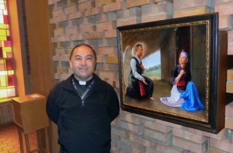 Father Toulee Peter Ly, pastor of Presentation of the Virgin Mary in Maplewood, stands beside a painting of “Hmong Mary” in the church. The painting was commissioned by Father Joseph Johnson, rector of the Cathedral of St. Paul and former pastor of St. Vincent de Paul, a former home of the Hmong Catholic community that was part of the Cathedral community.