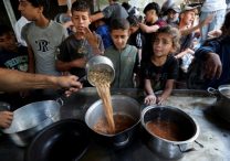 Young Palestinians displaced by the Israeli military offensive react May 21, 2025, while waiting to receive food cooked by a charity kitchen in Gaza City, Gaza Strip.