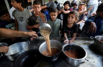 Young Palestinians displaced by the Israeli military offensive react May 21, 2025, while waiting to receive food cooked by a charity kitchen in Gaza City, Gaza Strip.