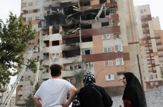 People look at a damaged building in Tehran, Iran, June 13, 2025, in the aftermath of Israeli airstrikes. Israel attacked Iran early that morning in strikes that took out top military officers and hit nuclear and missile sites, raising the potential for an all-out war between the two bitter Middle East adversaries. It appeared to be the most significant attack Iran has faced since its 1980s war with Iraq.