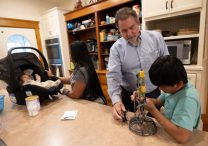 Joe Hammell, a retired attorney and volunteer with Ignatian Volunteer Corps, spends time with a family at Casa Guadalupana in St. Paul Aug. 22.