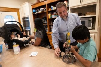 Joe Hammell, a retired attorney and volunteer with Ignatian Volunteer Corps, spends time with a family at Casa Guadalupana in St. Paul Aug. 22.