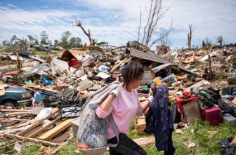 A woman carries belongings from a destroyed home in the Sunshine Hills neighborhood in London, Ky., May 18, 2025, after a series of tornadoes hit the area May 16. At least 27 people have been killed by storm systems that swept across part of the U.S. Midwest and South, with Kentucky Gov. Andy Beshear announcing May 17 that 18 of the deaths came in his state and 10 others were hospitalized in critical condition.