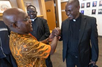 Father John Mbua Mwandi of the Diocese of Kitui, Kenya, right, greets George Mutua, left, May 11 at St. Gerard Majella in Brooklyn Park following a Mass to celebrate the 20th anniversary of a partnership between the Archdiocese of St. Paul and Minneapolis and the Diocese of Kitui. Another member of the delegation from Kitui was Father George Marete, center.