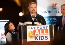 Alex Sobieski, center, and his daughter, Anna, left, address people gathered for a rally May 7 at the Minnesota State Capitol in St. Paul to support nonpublic school education.  Anna is a fifth grader at St. Agnes School in St. Paul who has three siblings enrolled there. She relies on a school nurse to help her address health conditions that make staying in school every day difficult. Gov. Tim Walz has proposed budget cuts that would eliminate state support for essential services at private schools, including school nurses. At right is Tim Benz, president of Minndependent, an organization that supports private and independent schools. Minndependent and the Minnesota Catholic Conference co-sponsored the event, which was called Rally and Advocacy Day.  DAVE HRBACEK  | THE CATHOLIC SPIRIT
