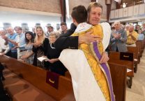 Tom Ochsenbauer reacts at the end of the Mass of Thanksgiving as he hugs his son, Father Zachary Ochsenbauer, shortly after receiving a special stole that is a tradition among newly ordained priests.  DAVE HRBACEK  |  THE CATHOLIC SPIRIT
