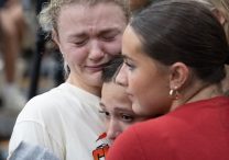 Ellie Mertens, left, youth minister at Annunciation church in Minneapolis, hugs others attending a prayer service at the Academy of Holy Angels in Richfield Aug. 27 to support those affected by a shooting at the church that morning, Mertens was at the Mass in the church when the shooting occurred.