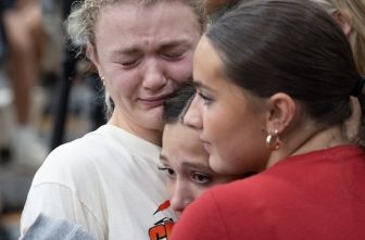 Ellie Mertens, left, youth minister at Annunciation church in Minneapolis, hugs others attending a prayer service at the Academy of Holy Angels in Richfield Aug. 27 to support those affected by a shooting at the church that morning, Mertens was at the Mass in the church when the shooting occurred.