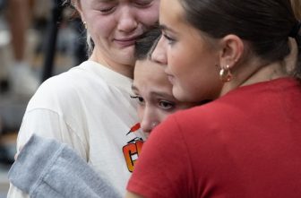 Ellie Mertens, left, youth minister at Annunciation church in Minneapolis, hugs others attending a prayer service at the Academy of Holy Angels in Richfield Aug. 27 to support those affected by a shooting at the church that morning, Mertens was at the Mass in the church when the shooting occurred. DAVE HRBACEK  |  THE CATHOLIC SPIRIT