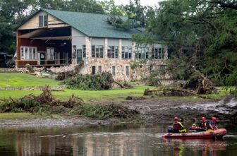 Search teams continue searching for flood victims in front of the main building at Camp Mystic in Kerr County, Texas, July 7, 2025, in the aftermath of deadly flooding. Flash floods in Texas killed more than 100 people over the Fourth of July holiday weekend, including girls attending a summer camp, and left others still missing.