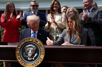 U.S. President Donald Trump looks on as first lady Melania Trump signs the Take it Down Act during a ceremony in the Rose Garden at the White House in Washington May 19, 2025. President Trump signed the bipartisan, bicameral bill into law, which prohibits the nonconsensual online publication of sexually explicit images and videos, whether they are authentic or computer-generated. The president then invited the first lady to add her signature because she had advocated for the measure.